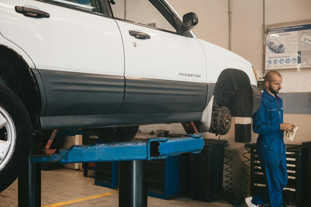 Mechanic evaluating a car on a lift for maintenance in an auto workshop.